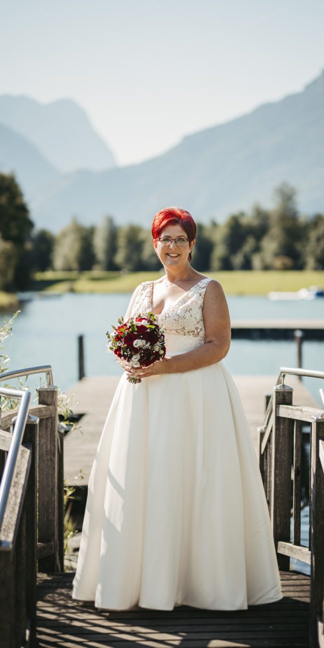 Brautpaar Gerhard und Daniela posiert für Familienfotos am Badesee Kuchl, umgeben von ihrer Hochzeitsgesellschaft.