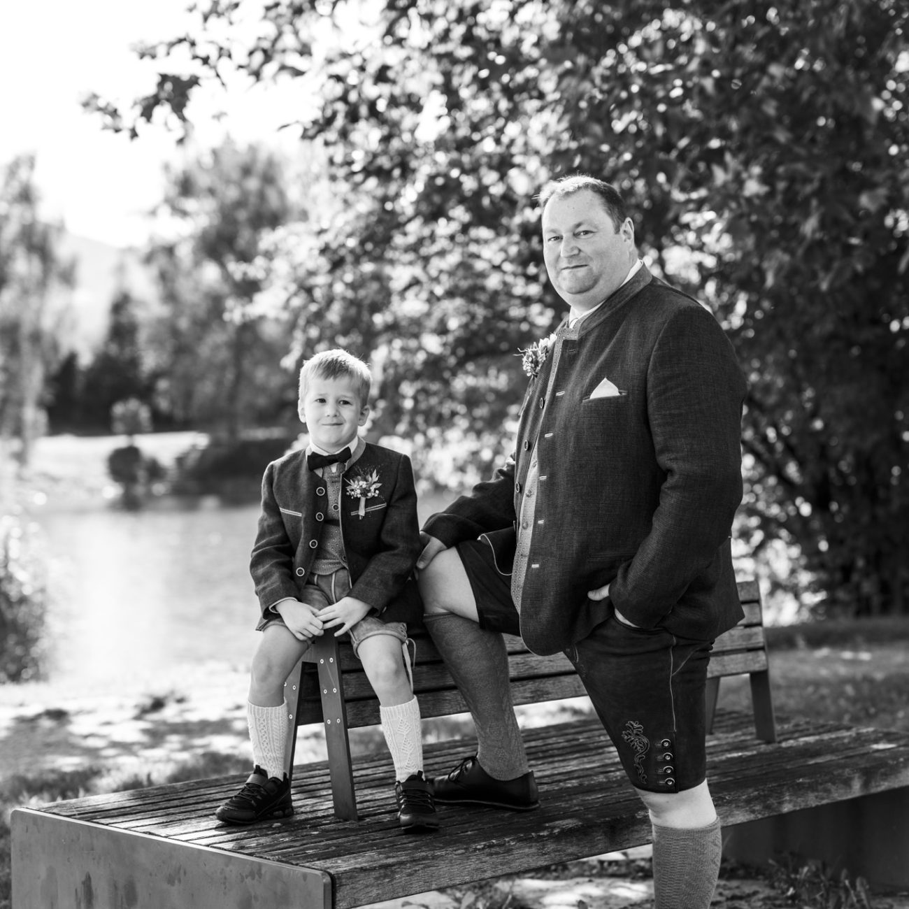 Brautpaar Gerhard und Daniela posiert für Familienfotos am Badesee Kuchl, umgeben von ihrer Hochzeitsgesellschaft.
