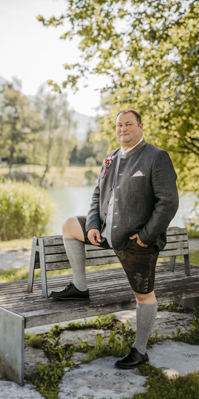 Brautpaar Gerhard und Daniela posiert für Familienfotos am Badesee Kuchl, umgeben von ihrer Hochzeitsgesellschaft.