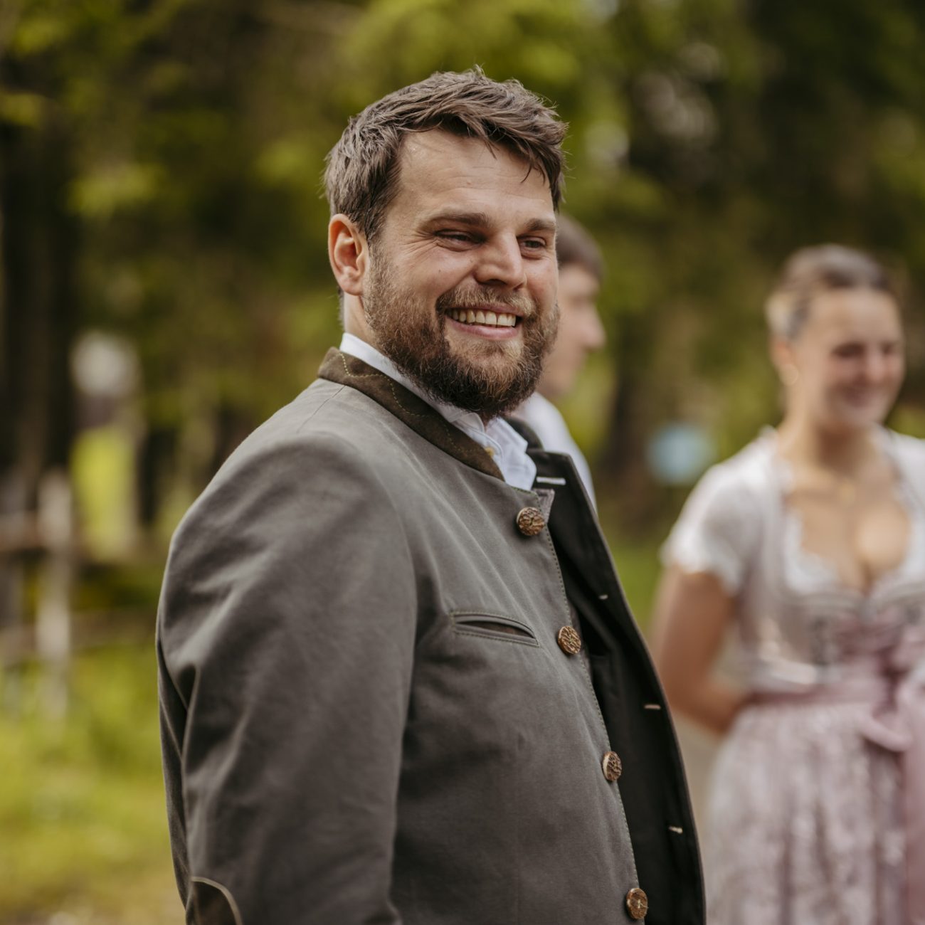 Julia und Andreas bei ihrer Hochzeit auf der Hatzalm in Hintersee in traditioneller Tracht mit Bergkulisse im Hintergrund.