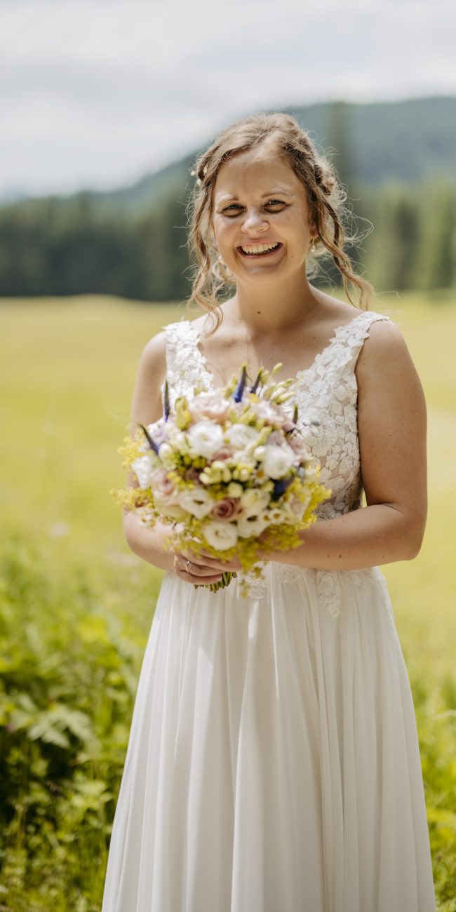 Julia und Andreas bei ihrer Hochzeit auf der Hatzalm in Hintersee in traditioneller Tracht mit Bergkulisse im Hintergrund.