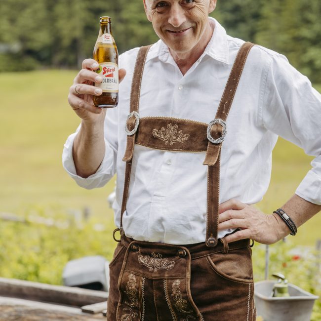 Julia und Andreas bei ihrer Hochzeit auf der Hatzalm in Hintersee in traditioneller Tracht mit Bergkulisse im Hintergrund.