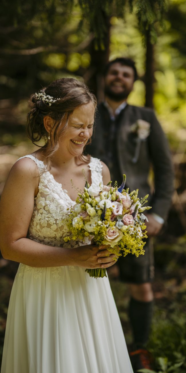Julia und Andreas bei ihrer Hochzeit auf der Hatzalm in Hintersee in traditioneller Tracht mit Bergkulisse im Hintergrund.