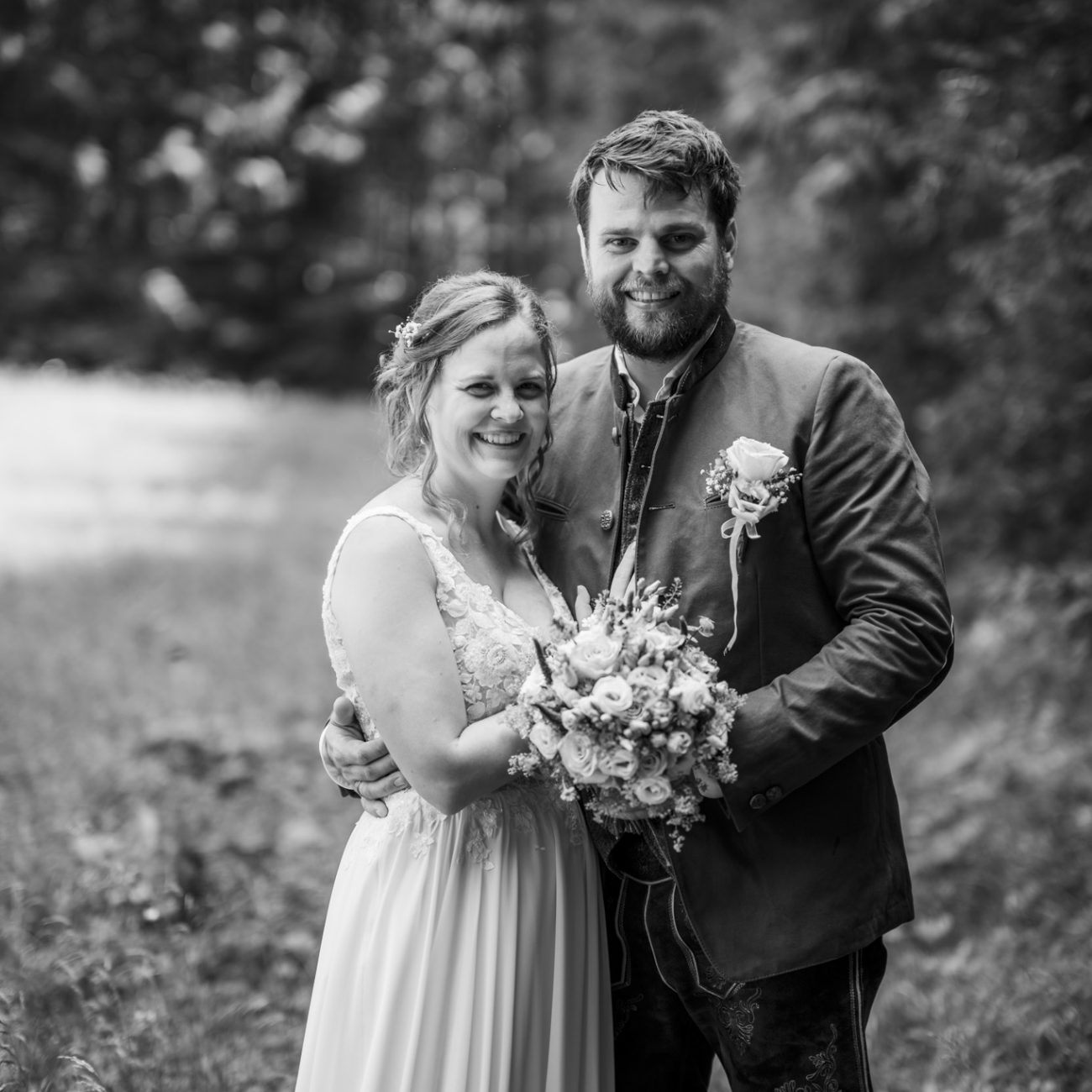 Julia und Andreas bei ihrer Hochzeit auf der Hatzalm in Hintersee in traditioneller Tracht mit Bergkulisse im Hintergrund.