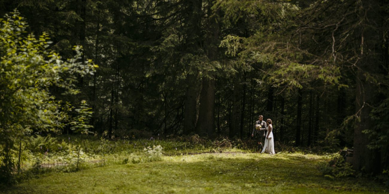 Julia und Andreas bei ihrer Hochzeit auf der Hatzalm in Hintersee in traditioneller Tracht mit Bergkulisse im Hintergrund.